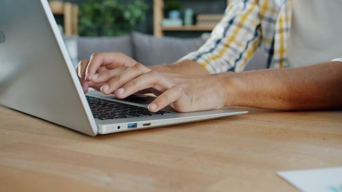 Hands typing on a laptop at a kitchen table